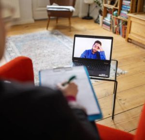 Man having mental health problems explaining his issues with a psychologist during cognitive behavioral therapy. Man having a video call with mental health professional.